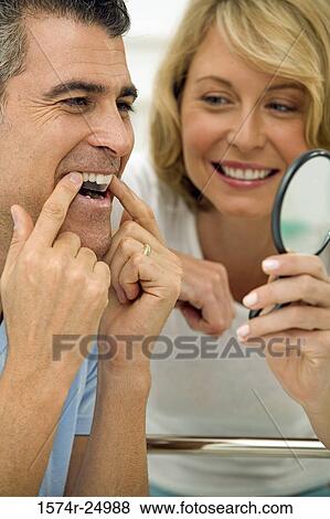 Close-up of a mature man applying a teeth whitening strip to his teeth with a mid adult woman holding a mirror View Large Photo Image Stock Photo - Close-up of a mature man applying a teeth whitening strip to his teeth with a mid adult woman holding a mirror. Fotosearch