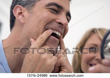 Close-up of a mature man applying a teeth whitening strip to his teeth with a mid adult woman beside him View Large Photo Image Stock Photograph - Close-up of a mature man applying a teeth whitening strip to his teeth with a mid adult woman beside him. Fotosearch