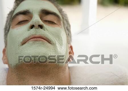 Picture - Close-up of a mature man wearing a facial mask and relaxing in a bathtub. Fotosearch