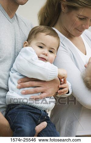 Close-up of a mid adult couple holding their children View Large Photo Image Stock Photograph - Close-up of a mid adult couple holding their children. Fotosearch