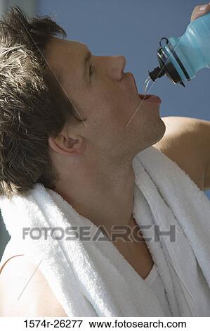 Stock Photo - Close-up of a mid adult man drinking from a water bottle. Fotosearch