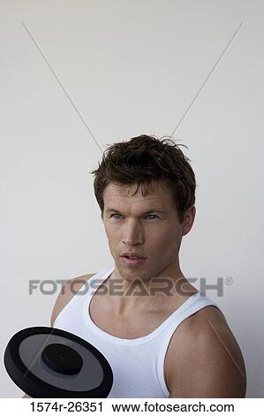 Stock Image - Close-up of a mid adult man with a dumbbell. Fotosearch