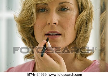 Close-up of a mid adult woman applying lipstick to her lips View Large Photo Image Stock Photo - Close-up of a mid adult woman applying lipstick to her lips. Fotosearch