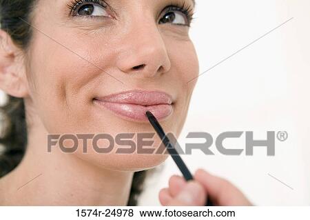 Close-up of a mid adult woman applying lipstick to her lips with a make-up brush View Large Photo Image Stock Photo - Close-up of a mid adult woman applying lipstick to her lips with a make-up brush. Fotosearch