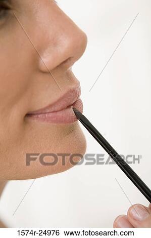 Close-up of a mid adult woman applying lipstick to her lips with a make-up brush View Large Photo Image Stock Photograph - Close-up of a mid adult woman applying lipstick to her lips with a make-up brush. Fotosearch