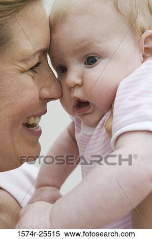Close-up of a mid adult woman cuddling with her daughter View Large Photo Image Stock Photography - Close-up of a mid adult woman cuddling with her daughter. Fotosearch