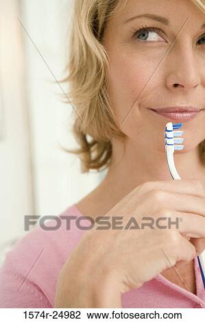Close-up of a mid adult woman holding a toothbrush View Large Photo Image Stock Image - Close-up of a mid adult woman holding a toothbrush. Fotosearch