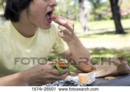 Close-up of a young man eating View Large Photo Image Stock Image - Close-up of a young man eating. Fotosearch