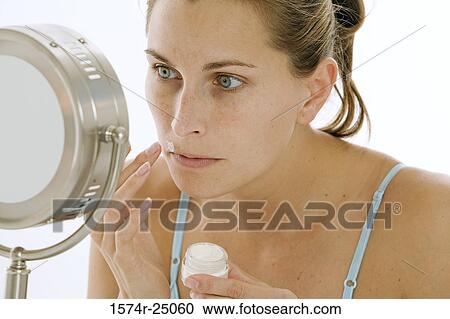 Close-up of a young woman applying cream to her face View Large Photo Image Stock Image - Close-up of a young woman applying cream to her face. Fotosearch