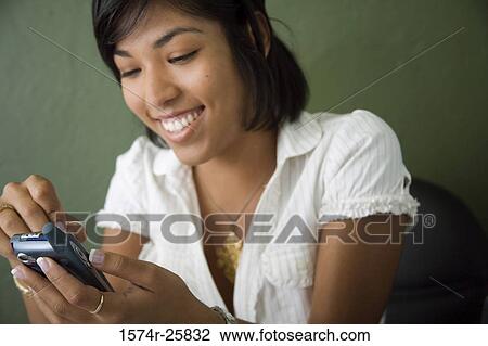 Close-up of a young woman operating a personal data assistant View Large Photo Image Stock Image - Close-up of a young woman operating a personal data assistant. Fotosearch