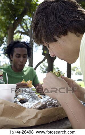 Close-up of two young men eating View Large Photo Image Stock Photo - Close-up of two young men eating. Fotosearch