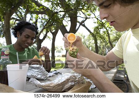 Stock Photo - Close-up of two young men eating. Fotosearch