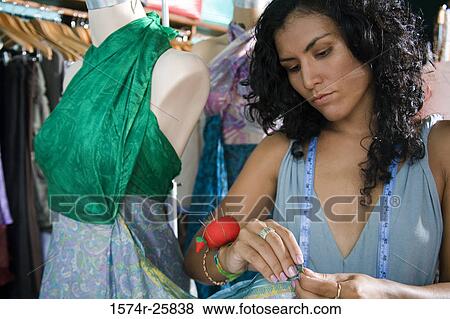 Female fashion designer working on a dress on a mannequin View Large Photo Image Stock Photo - Female fashion designer working on a dress on a mannequin. Fotosearch