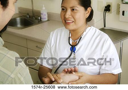 Female nurse checking the pulse of a patient and smiling View Large Photo Image Stock Photo - Female nurse checking the pulse of a patient and smiling. Fotosearch