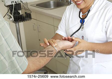 Stock Photo - Female nurse checking the pulse of a patient. Fotosearch