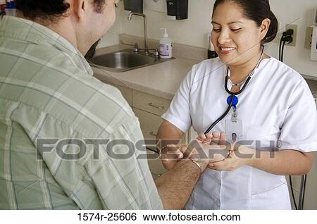 Female nurse checking the pulse of a patient and smiling View Large Photo Image Stock Photograph - Female nurse checking the pulse of a patient and smiling. Fotosearch