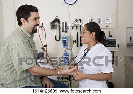 Stock Photography - Female nurse checking the pulse of a patient and smiling. Fotosearch