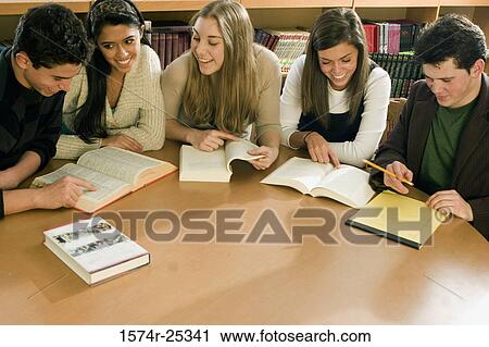 Stock Image - Five students sitting at a table in a library. Fotosearch