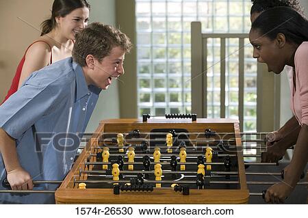 Four people playing foosball View Large Photo Image Stock Image - Four people playing foosball. Fotosearch
