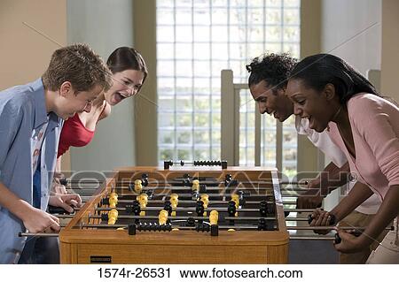 Four people playing foosball View Large Photo Image Stock Image - Four people playing foosball. Fotosearch