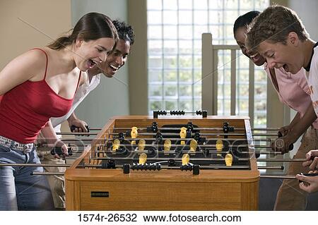 Four people playing foosball View Large Photo Image Stock Image - Four people playing foosball. Fotosearch