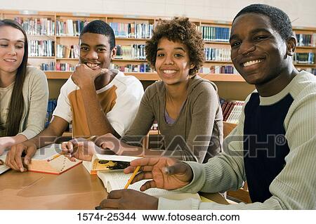 Picture - Four students sitting at a table in a library. Fotosearch