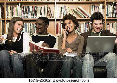 Stock Image - Four students sitting on a couch in a library. Fotosearch