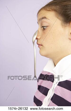 Stock Image - Girl balancing a spoon on her nose. Fotosearch