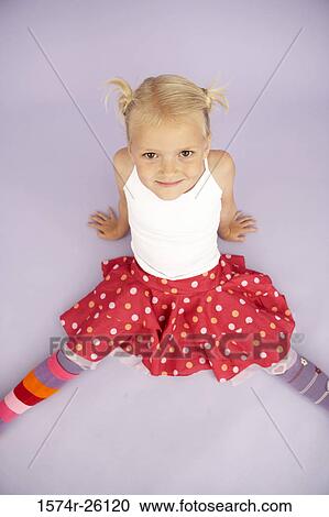 Stock Image - High angle of a girl wearing stockings of two different colors and reclining on the floor. Fotosearch