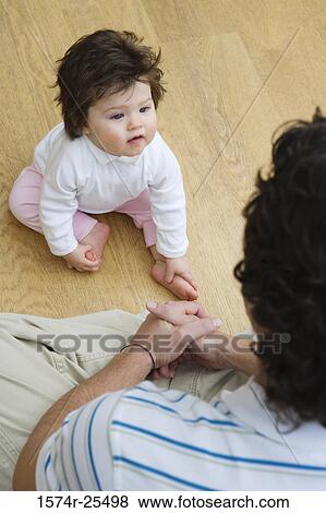 Stock Photo - High angle view of a baby girl sitting in front of her father. Fotosearch