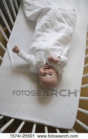 High angle view of a baby lying in a crib View Large Photo Image Stock Image - High angle view of a baby lying in a crib. Fotosearch