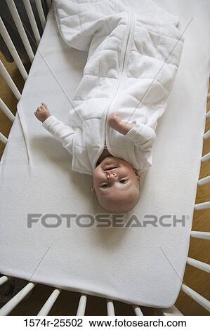 Stock Image - High angle view of a baby lying in a crib. Fotosearch