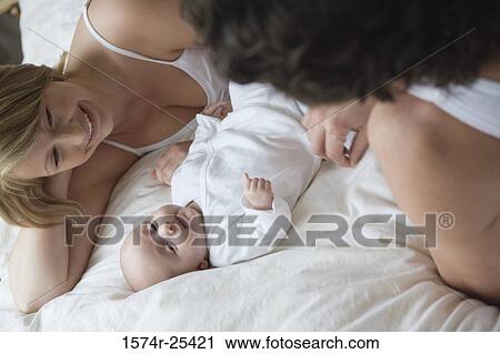 High angle view of a mid adult couple lying in bed with their baby View Large Photo Image Stock Image - High angle view of a mid adult couple lying in bed with their baby. Fotosearch