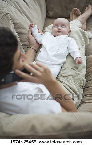 High angle view of a mid adult man using a mobile phone with his baby on his lap View Large Photo Image Stock Photography - High angle view of a mid adult man using a mobile phone with his baby on his lap. Fotosearch