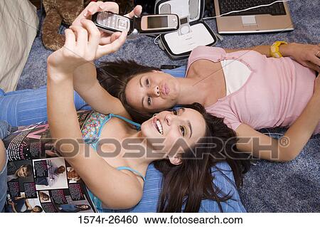 Stock Image - High angle view of a teenage girl and a young woman photographing themselves. Fotosearch