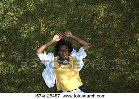 Stock Photo - High angle view of a young man lying on grass. Fotosearch