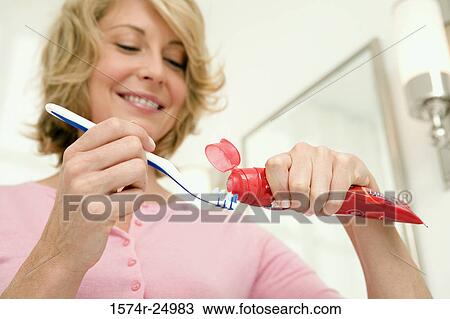Low angle view of a mid adult woman putting toothpaste on a toothbrush View Large Photo Image Stock Image - Low angle view of a mid adult woman putting toothpaste on a toothbrush. Fotosearch
