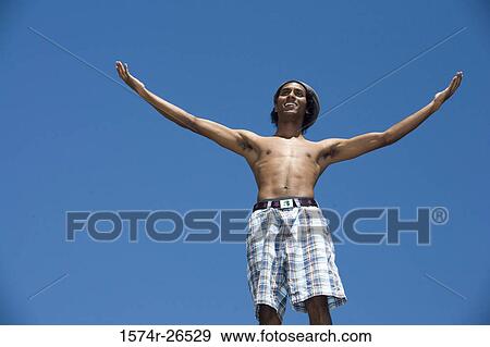 Low angle view of a young man gesturing View Large Photo Image Stock Photo - Low angle view of a young man gesturing. Fotosearch