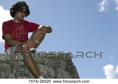 Low angle view of a young man listening to music View Large Photo Image Stock Image - Low angle view of a young man listening to music. Fotosearch