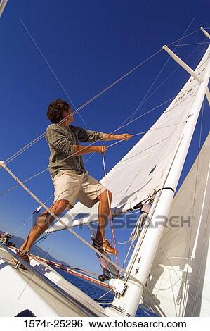Low angle view of a young man standing on a sailboat and pulling a rope View Large Photo Image Stock Photograph - Low angle view of a young man standing on a sailboat and pulling a rope. Fotosearch