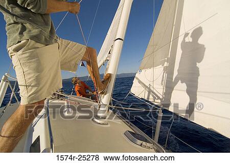 Low section view of a man pulling a rope on a sailboat View Large Photo Image Stock Photo - Low section view of a man pulling a rope on a sailboat. Fotosearch