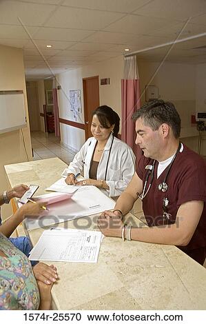 Male doctor and a female doctor standing at counter View Large Photo Image Stock Image - Male doctor and a female doctor standing at counter. Fotosearch