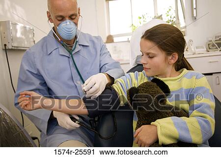 Stock Image - Male doctor checking the blood pressure of a patient. Fotosearch