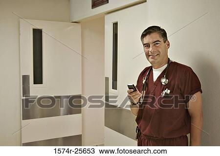 Male doctor holding a mobile phone and smiling View Large Photo Image Stock Image - Male doctor holding a mobile phone and smiling. Fotosearch