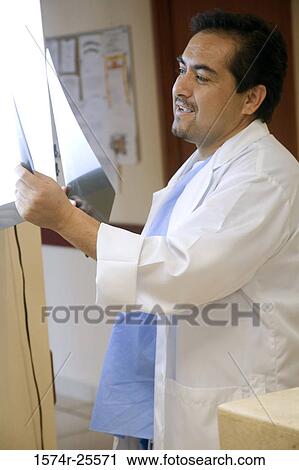 Stock Image - Male doctor looking at an x-ray image. Fotosearch