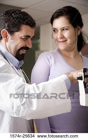 Male doctor measuring the weight of a patient and smiling View Large Photo Image Picture - Male doctor measuring the weight of a patient and smiling. Fotosearch
