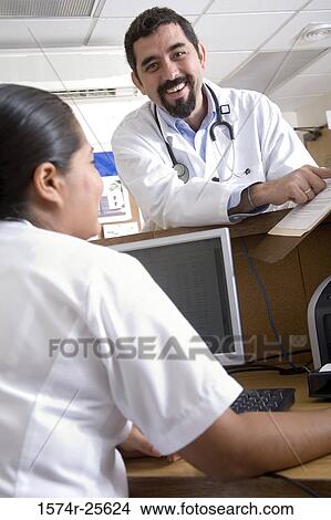 Picture - Male doctor showing the report to a female nurse. Fotosearch