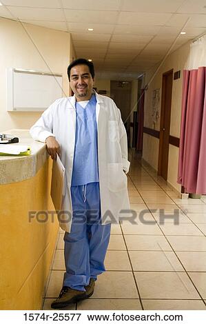 Male doctor standing at a counter and smiling View Large Photo Image Stock Photo - Male doctor standing at a counter and smiling. Fotosearch