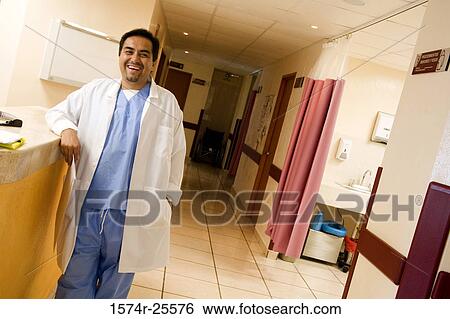 Male doctor standing at a counter and smiling View Large Photo Image Stock Photograph - Male doctor standing at a counter and smiling. Fotosearch