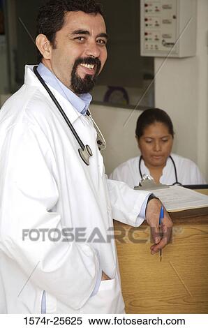 Stock Photography - Male doctor standing at a counter and smiling. Fotosearch